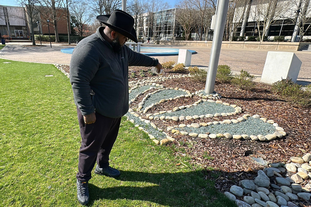 Eddie Flack pour out a bottle of whiskey at the base of the flagpoles in front of Constant Hall as he pays respect to slain Lt. Col. Brandon Shah at Old Dominion University on Friday, March 13, 2026 in Norfolk, Va. (AP Photo/Allen G. Breed)