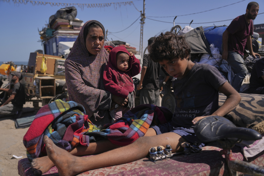 Amal Al-Qishawi, follows her injured son, Yasser, 11, carried on a bicycle by his father Rafiq Al-Qishawi, as they flee northern Gaza Strip walking along the coastal road, near Wadi Gaza, Saturday, Sept. 20, 2025. (AP Photo/Abdel Kareem Hana)
