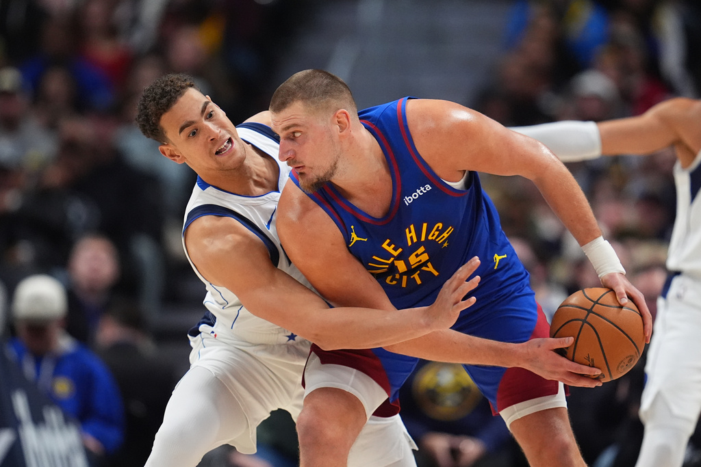 Dallas Mavericks center Dwight Powell, left, defends against Denver Nuggets center Nikola Jokić, right, in the first half of an NBA basketball game Monday, Dec. 1, 2025, in Denver. (AP Photo/David Zalubowski)