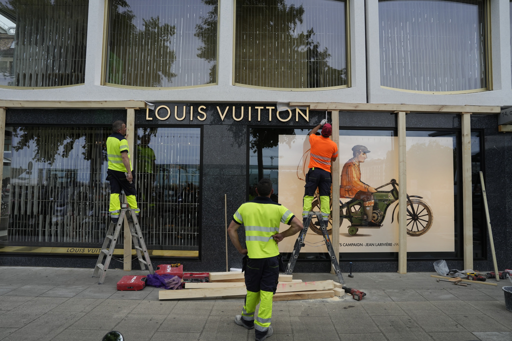 Construction workers board up a shop window, ahead of expected protests for the G7 summit, in Geneva, Switzerland, Monday, June 8, 2026. (AP Photo/Baz Ratner)