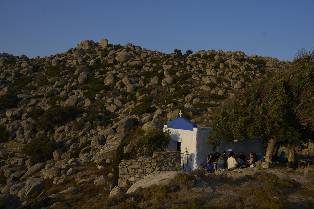 Tourists from the United States enjoy an organized picnic outside Agios Giorgos (St. George), a 200-year-old chapel near the village of Volax on Tinos island, Greece, Friday, Sept. 5, 2025. (AP Photo/Petros Giannakouris)
