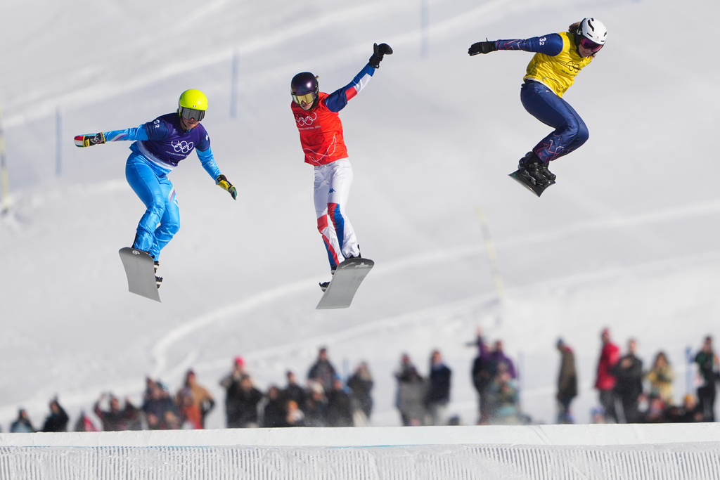 From left, Italy's Michela Moioli (6-2), France's Lea Casta (1-2) and Britain's Charlotte Bankes (13-2) compete during the mixed team snowboard cross finals at the 2026 Winter Olympics, in Livigno, Italy, Sunday, Feb. 15, 2026. (AP Photo/Lindsey Wasson)