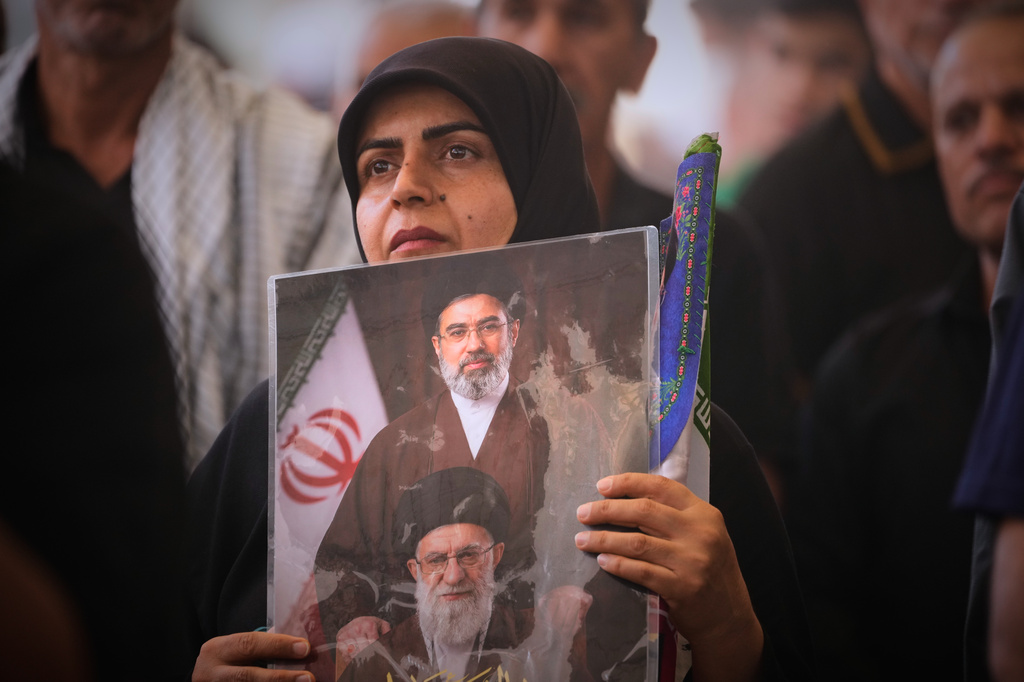 A mourner holds a portrait depicting Iran's Supreme Leader Ayatollah Mojtaba Khamenei, top, and his late father, Ayatollah Ali Khamenei, during a funeral procession for the elder Khamenei inside the Imam Ali Shrine in Najaf, Iraq, Wednesday, July 8, 2026. (AP Photo/Hadi Mizban)