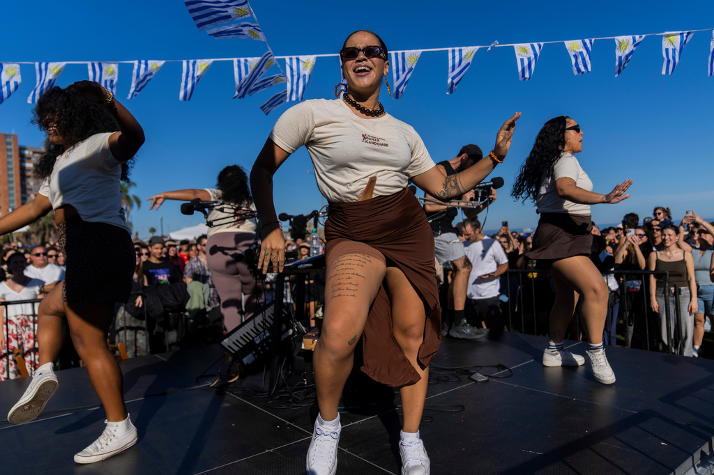 Dancers teach spectators how to dance as musicians perform during the Rueda de Candombe at Plaza Espana in Montevideo, Uruguay, Sunday, April 19, 2026. (AP Photo/Matilde Campodonico)