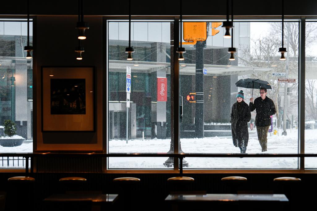 People walk through Arlington, Va. during a snowstorm, Sunday, Jan. 25, 2026. (AP Photo/Julia Demaree Nikhinson)