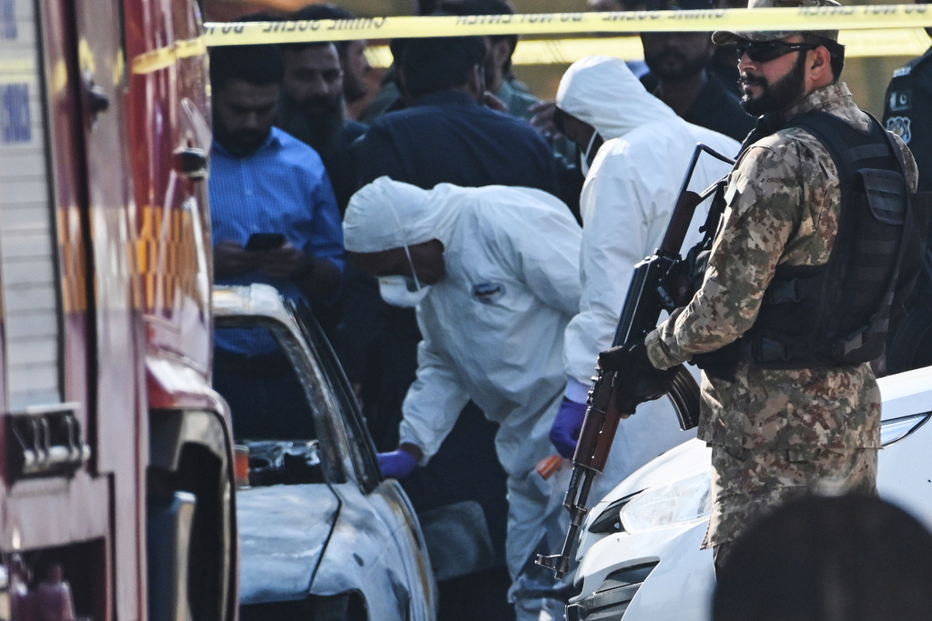 Pakistani investigators examine a damaged car at the site of a suicide bombing outside the gates of a district court, in Islamabad, Pakistan, Tuesday, Nov. 11, 2025. (AP Photo/Ahsan Shahzad)