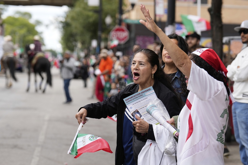 People wave flags a s they watch during the 2025 Pilsen Mexican Independence Day parade Saturday, Sept. 6, 2025, in Chicago. (AP Photo/Carolyn Kaster)