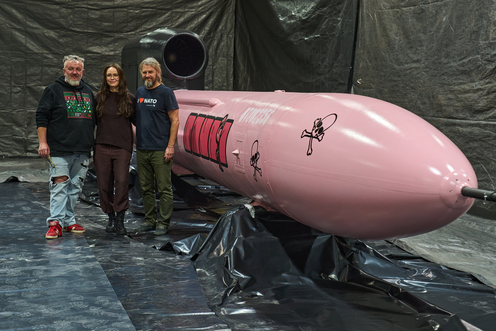 Jan Polak, right, and Martin Ondracek, left, from the Czech organization, Weapons to Ukraine, together with Iryna Terekh, Chief Technology Officer of the Fire Point factory, center, pose for photo by a Flamingo cruise missile, which was paid for by Czech crowdfunding campaign, at the Fire Point factory at an undisclosed location in Ukraine, Sunday, Nov. 16, 2025. (AP Photo/Efrem Lukatsky)