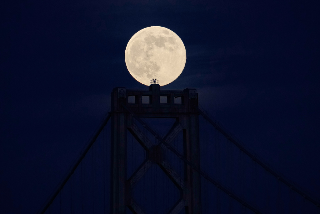A supermoon, the last full moon of the year, rises behind the San Francisco-Oakland Bay Bridge, Thursday, Dec. 4, 2025, in San Francisco. (AP Photo/Godofredo A. Vásquez)