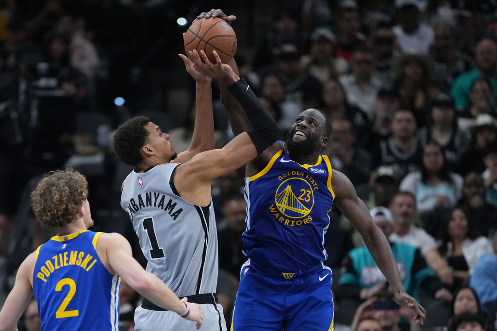 San Antonio Spurs forward Victor Wembanyama (1) is blocked by Golden State Warriors forward Draymond Green (23) during the second half of an NBA Cup basketball game in San Antonio, Friday, Nov. 14, 2025. (AP Photo/Eric Gay)