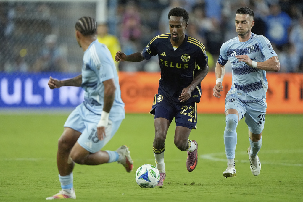 Vancouver Whitecaps midfielder Ali Ahmed (22) is chased by Sporting Kansas City midfielder Erik Thommy, right, during the second half of an MLS soccer match Saturday, Sept. 20, 2025, in Kansas City, Kan. (AP Photo/Charlie Riedel)
