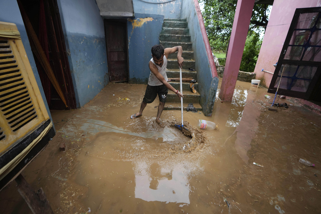 A man removes mud from his home after it was hit by flash floods on the outskirts of Jammu, India, Sunday, Aug. 24, 2025. (AP Photo/Channi Anand)