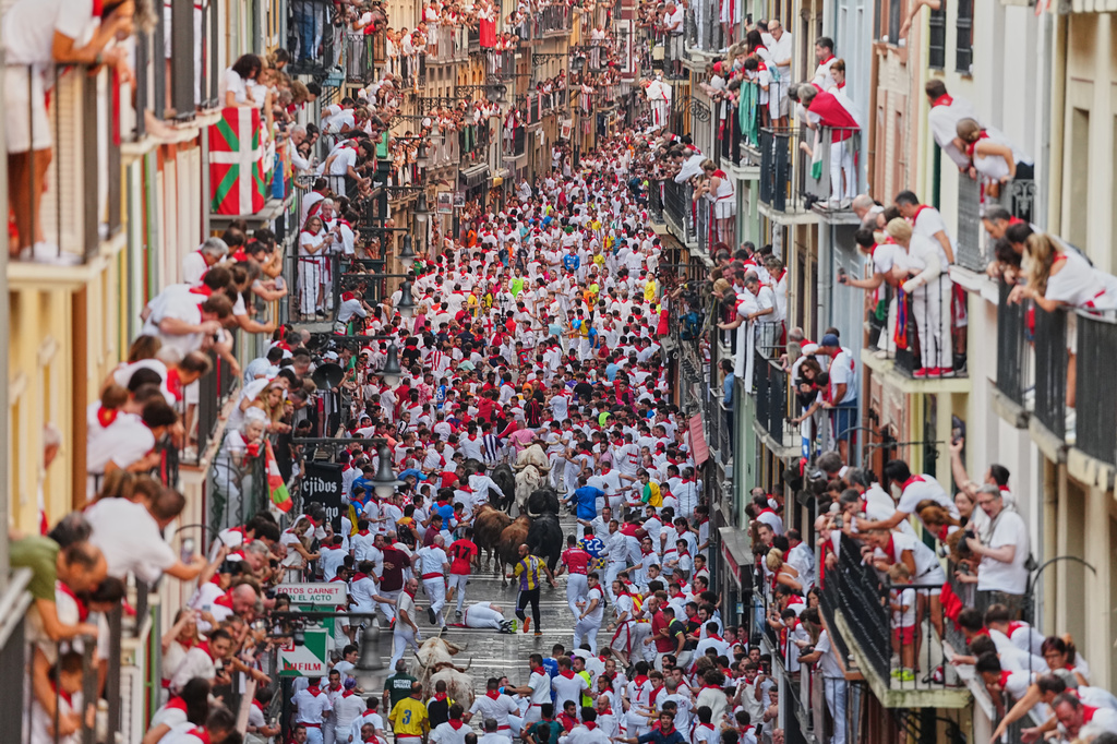 Revelers run alongside Victoriano del Río's fighting bulls during the third running of the bulls at the San Fermín festival in Pamplona, Spain, Thursday, July 9, 2026. (AP Photo/Miguel Oses)