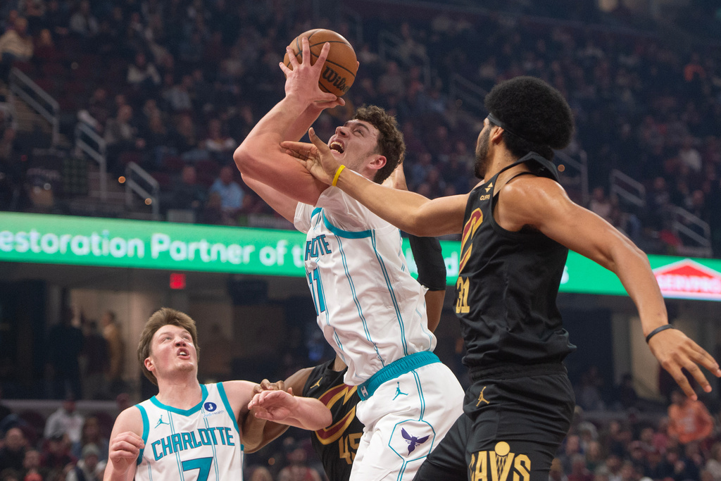 Charlotte Hornets' Ryan Kalkbrenner, center, grabs a rebound in front of Cleveland Cavaliers' Jarrett Allen, right, as Hornets' Kon Knueppel, left, watches during the first half of an NBA basketball game in Cleveland, Sunday, Dec. 14, 2025. (AP Photo/Phil Long)