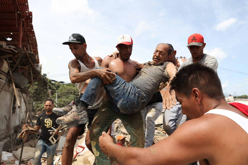 FILE - Neighbors carry a man rescued from the rubble of a collapsed building in La Guaira, Venezuela, June 25, 2026, a day after twin earthquakes struck the country. (AP Photo/Pedro Mattey, File)