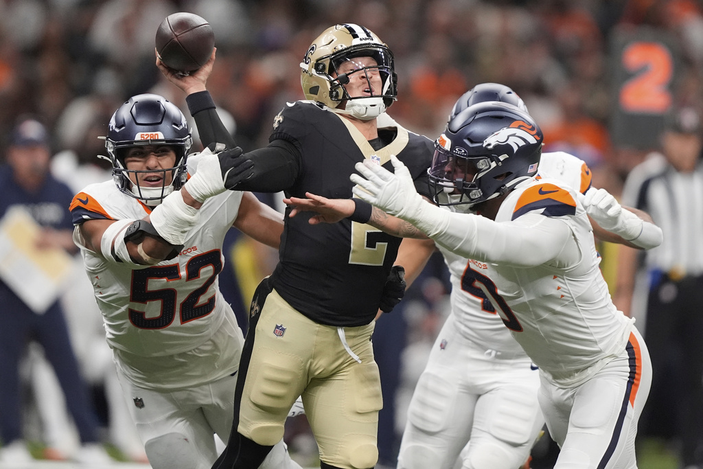 New Orleans Saints quarterback Spencer Rattler, center, is hit by Denver Broncos linebackers Jonah Elliss, left, Justin Strnad, back right, and Jonathon Cooper in the first half of an NFL preseason football game Saturday, Aug. 23, 2025, in New Orleans. (AP Photo/Gerlad Herbert)