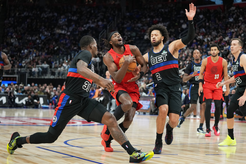 Portland Trail Blazers forward Jerami Grant, center, drives against Detroit Pistons guards Javonte Green, left, and Cade Cunningham during the first half of an NBA basketball game Friday, Dec. 5, 2025, in Detroit. (AP Photo/Ryan Sun)
