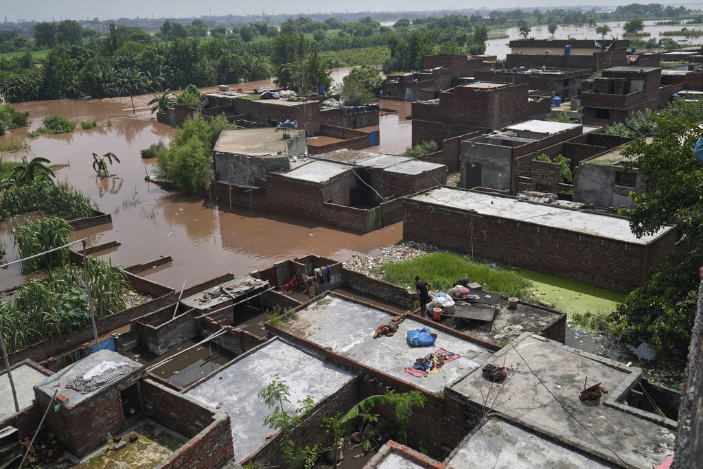 A resident retrieves belongings from his flooded home due to rising water level in Ravi River after torrential rains at a low-lying area on the outskirts of Lahore, Pakistan, Aug. 28, 2025. (AP Photo/K.M. Chaudary)