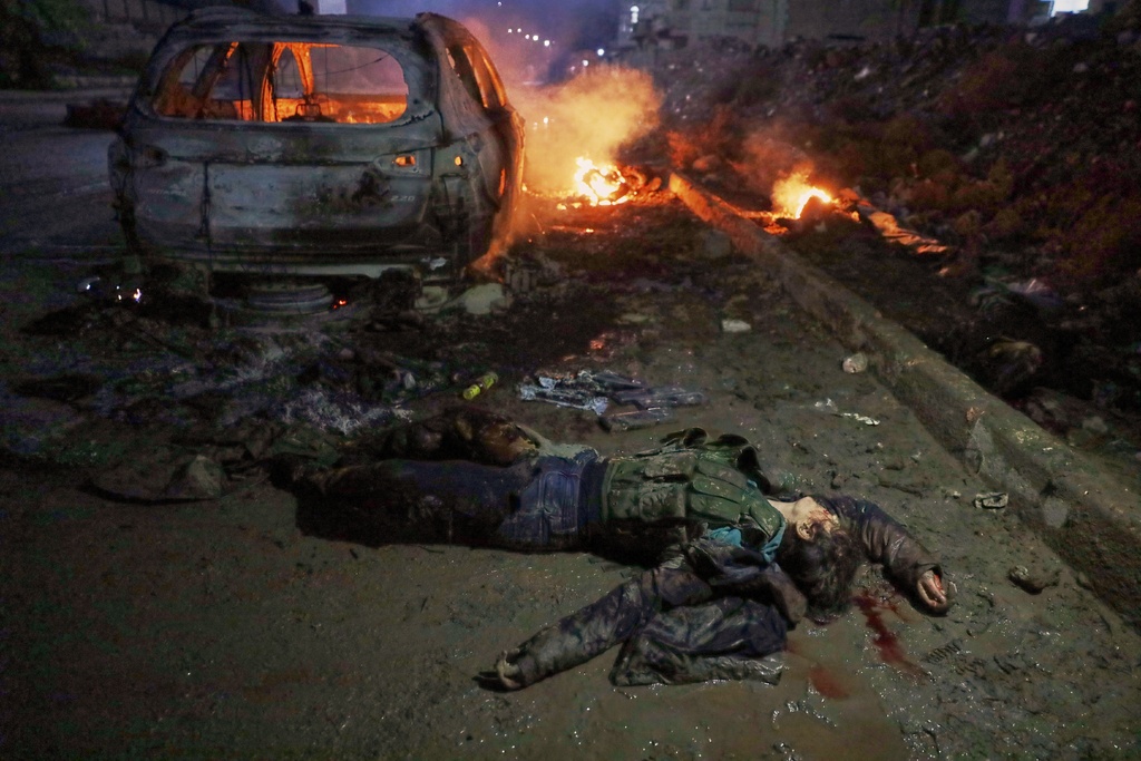 EDS NOTE: GRAPHIC CONTENT - The body of a female SDF fighter lies next to a burning car after Syrian government troops took control of the town from the Kurdish-led, U.S.-backed Syrian Democratic Forces (SDF), in Raqqa, northeastern Syria, Sunday, Jan. 18, 2026. (AP Photo/Omar Albam)