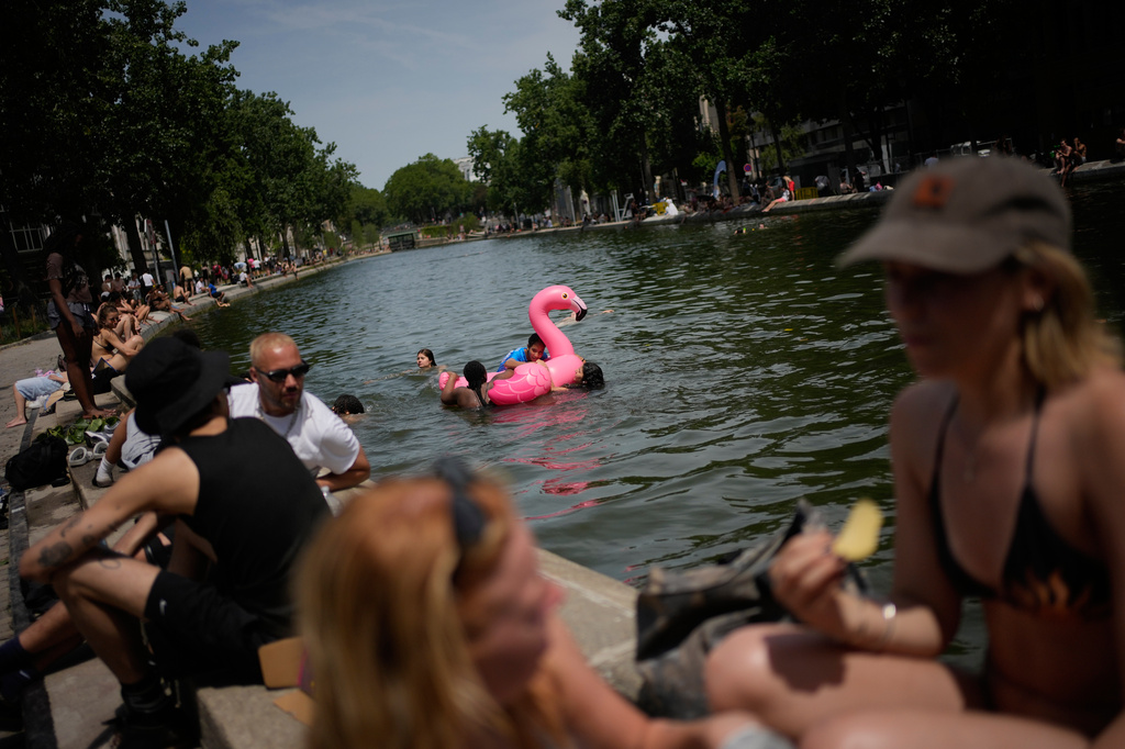 Parisians bath in the Canal Saint-Martin in Paris, as the national weather service, Meteo France, placed 54 departments, about half the country, under a red heat wave alert, Tuesday, June 23, 2026. (AP Photo/Christophe Ena )