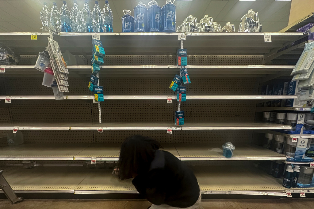 A shopper searches for water on near empty shelves in grocery store ahead of winter weather, Wednesday, Jan. 21, 2026, in Marietta, Ga. (AP Photo/Mike Stewart)