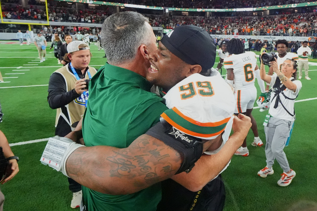 Miami head coach Mario Cristobal, left, hugs defensive lineman Ahmad Moten Sr. following the Cotton Bowl College Football Playoff quarterfinal game against Ohio State Wednesday, Dec. 31, 2025, in Arlington, Texas. (AP Photo/Julio Cortez)