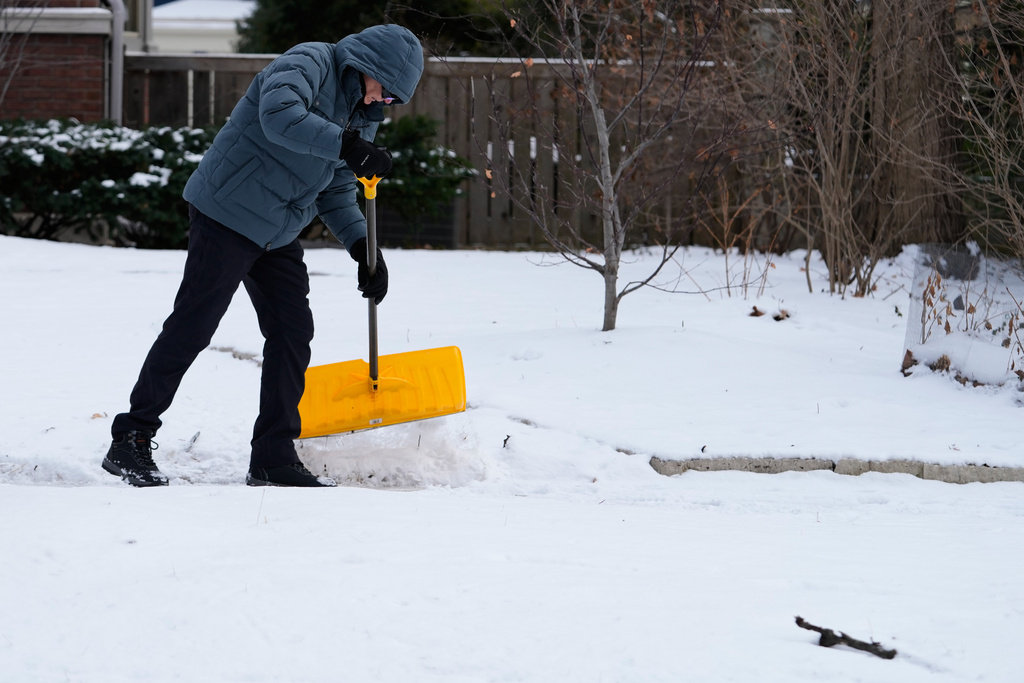 A person cleans snow during a cold weather in Evanston, Ill., Thursday, Jan. 22, 2026. (AP Photo/Nam Y. Huh)