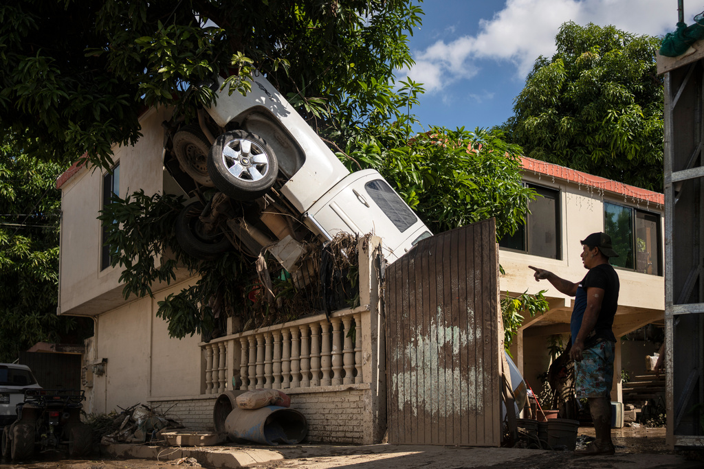 A pickup truck hangs over a fence in Poza Rica, Veracruz state, Mexico, Sunday, Oct. 12, 2025, after rain and flooding. (AP Photo/Felix Marquez)