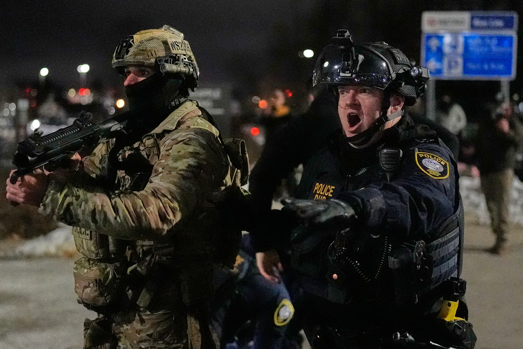 Federal immigration officers confront protesters outside Bishop Henry Whipple Federal Building, Thursday, Jan. 15, 2026, in Minneapolis. (AP Photo/Yuki Iwamura)