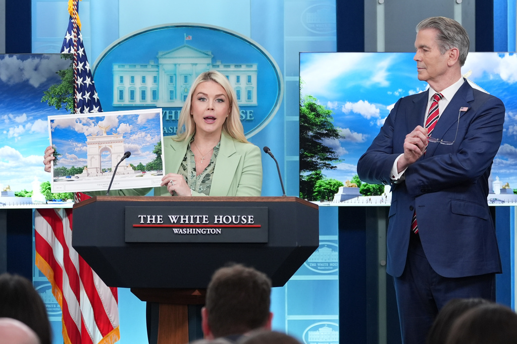 FILE - White House press secretary Karoline Leavitt holds up an artist rendering of the new triumphal arch as she speaks with reporters in the James Brady Press Briefing Room at the White House, April 15, 2026, in Washington, as Treasury Secretary Scott Bessent watches. (AP Photo/Alex Brandon, file)
