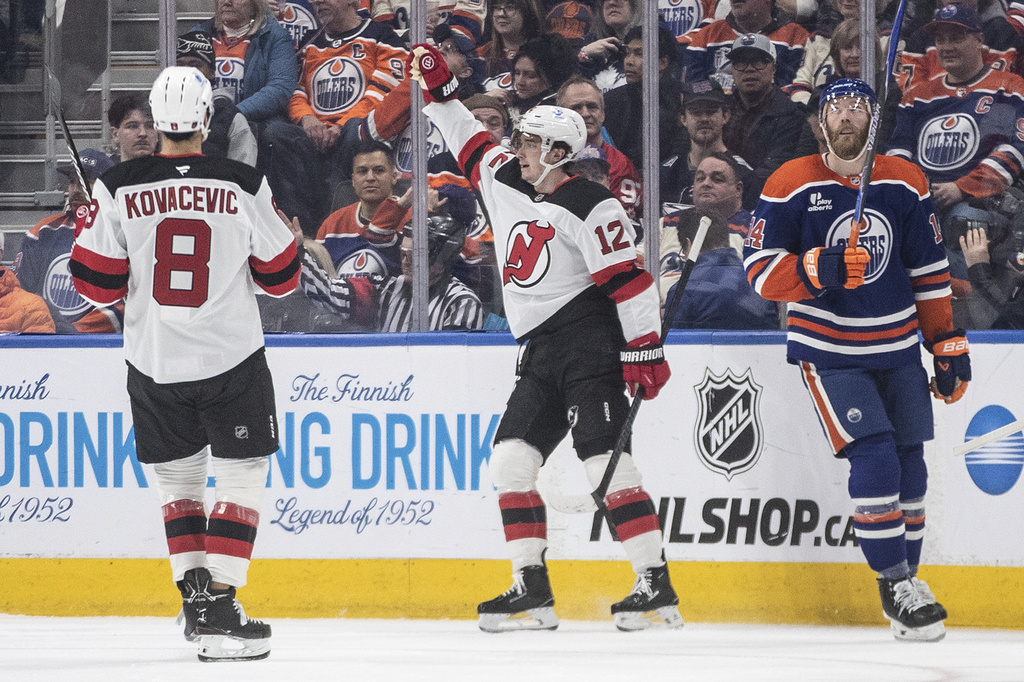 New Jersey Devils' Johnathan Kovacevic (8) and Cody Glass (12) celebrate a goal as Edmonton Oilers' Mattias Ekholm (14) looks on during the second period of an NHL hockey game in Edmonton, Alberta, on Tuesday, Jan. 20, 2026. (Jason Franson/The Canadian Press via AP)