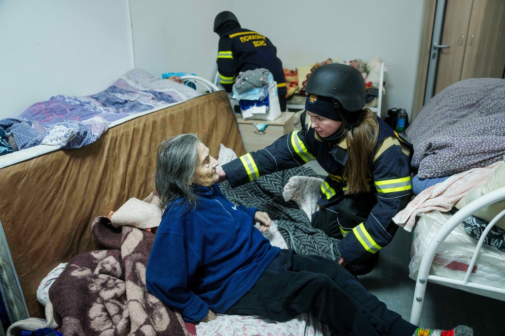 A psychologist of a rescue team helps en elderly woman at the hospice which was damaged after a Russian strike on Kyiv, Ukraine, on Saturday, Dec. 27, 2025. (AP Photo/Evgeniy Maloletka)