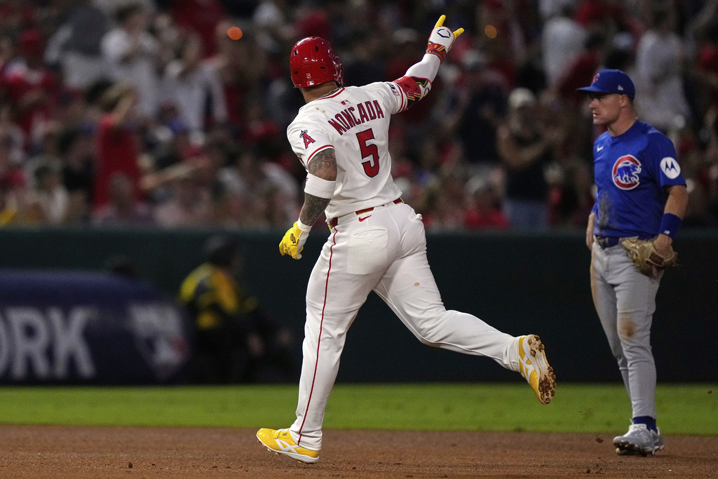 Los Angeles Angels' Yoan Moncada, left, gestures after hitting a solo home run as Chicago Cubs third baseman Matt Shaw stands by during the fifth inning of a baseball game Friday, Aug. 22, 2025, in Anaheim, Calif. (AP Photo/Mark J. Terrill)