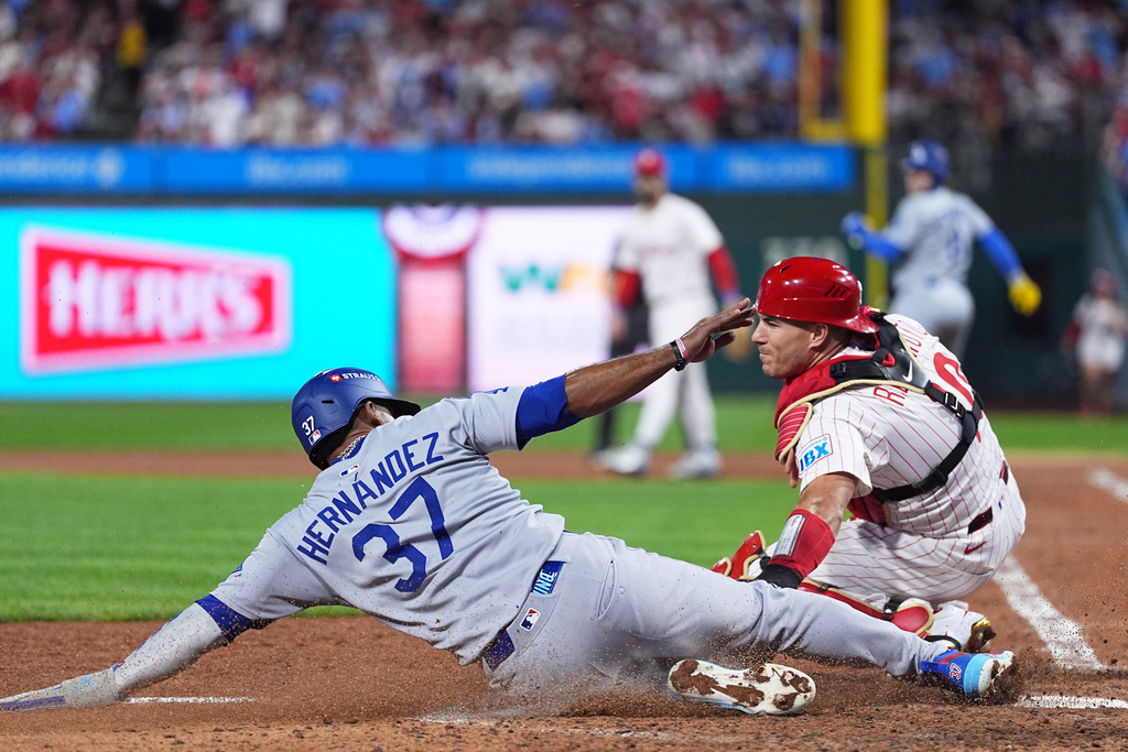 Los Angeles Dodgers' Teoscar Hernandez, left, slides home past Philadelphia Phillies catcher J.T. Realmuto to score off a fielder's choice off of a ground ball hit by Kiké Hernández during the seventh inning in Game 2 of baseball's National League Division Series, Monday, Oct. 6, 2025, in Philadelphia. (AP Photo/Matt Rourke)