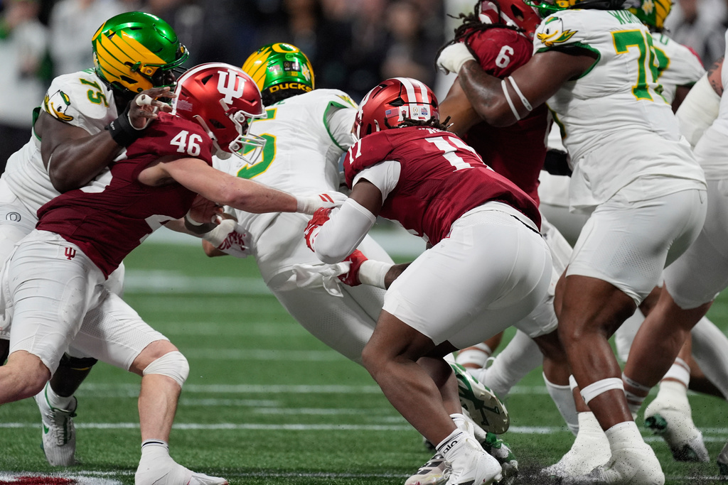 Oregon quarterback Dante Moore (5) is sacked by Indiana linebacker Isaiah Jones (46) and defensive lineman Daniel Ndukwe (17) during the first half of the Peach Bowl NCAA college football playoff semifinal, Friday, Jan. 9, 2026, in Atlanta. (AP Photo/Mike Stewart)