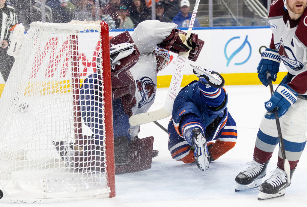 Colorado Avalanche goalie Scott Wedgewood (41) is knocked over by Edmonton Oilers' Kasperi Kapanen (42) during overtime NHL action, in Edmonton, Alberta, on Monday, April 13, 2026. (Jason Franson/The Canadian Press via AP)