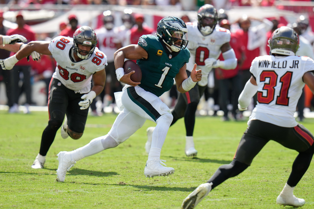 Philadelphia Eagles quarterback Jalen Hurts (1) rushes past Tampa Bay Buccaneers defensive line Logan Hall (90) during the second half of an NFL football game Sunday, Sept. 28, 2025, in Tampa, Fla. (AP Photo/Chris O'Meara)