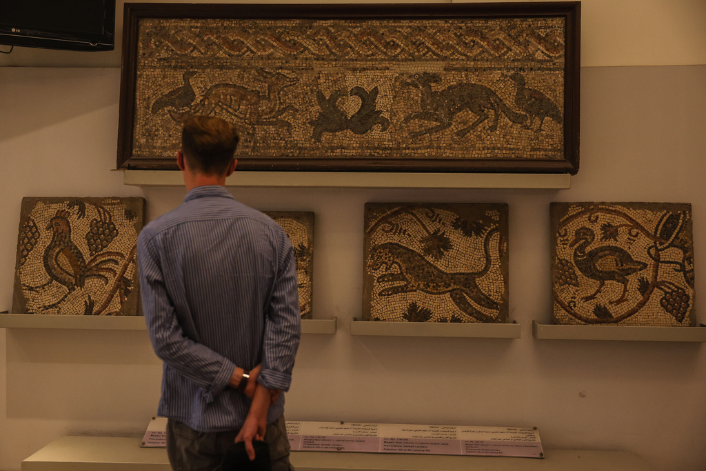 A visitor looks at ancient mosaics on display at the National Museum of Syria in Damascus, Friday, May 23, 2025. (AP Photo/Ghaith Alsayed)