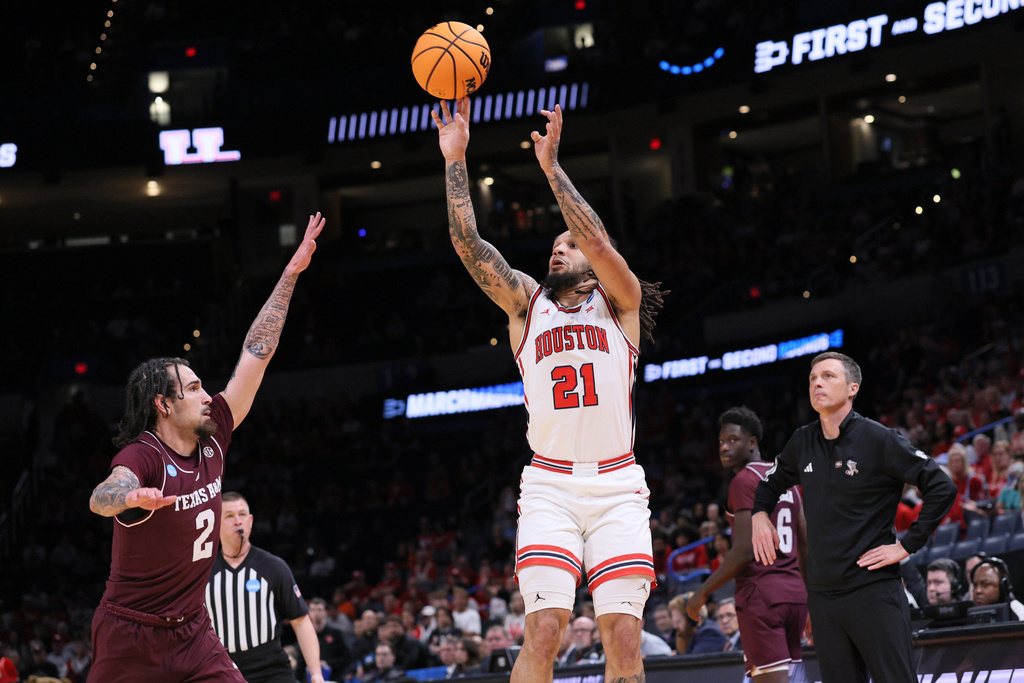 Houston guard Emanuel Sharp (21) shoots over Texas A&M guard Pop Isaacs (2) as Texas A&M head coach Bucky McMillan, right, watches during the first half in the second round of the NCAA college basketball tournament Saturday, March 21, 2026, in Oklahoma City. (AP Photo/Nate Billings)