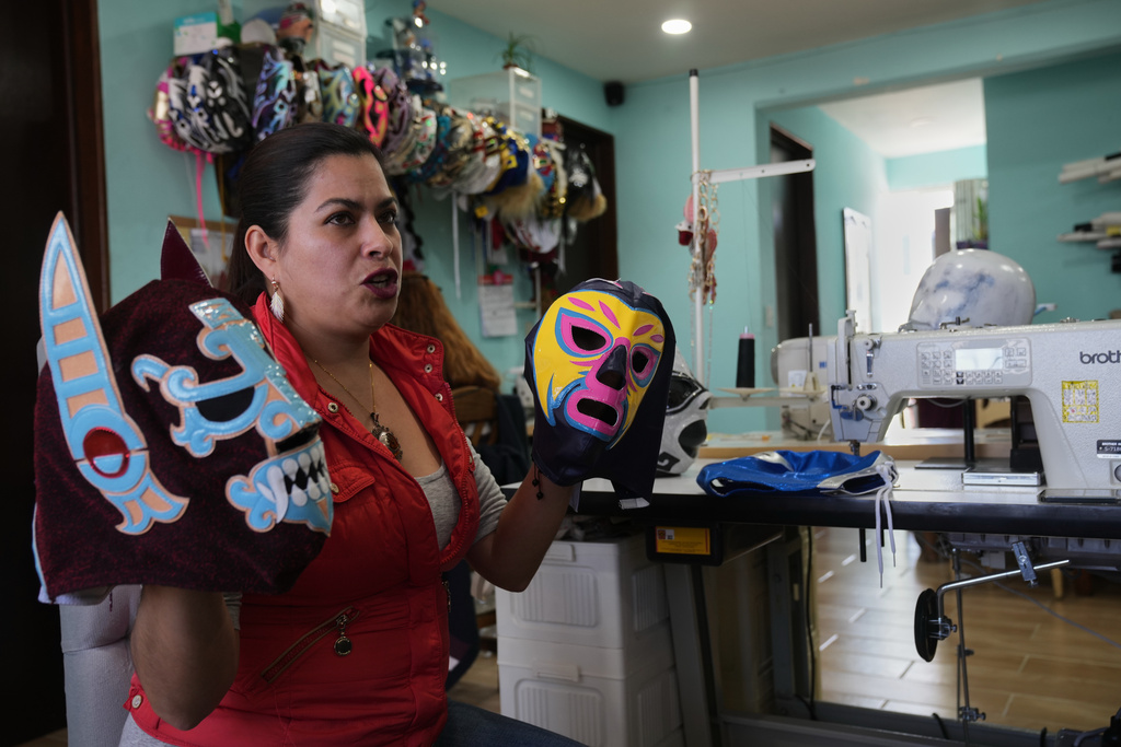 Alma Guadalupe Zuñiga, a wrestling mask artisan, displays the "Ultimo Guerrero," mask, left, and another she made for Formula 1, at her home workshop in Mexico City, Saturday, Feb. 7, 2026. (AP Photo/Marco Ugarte)