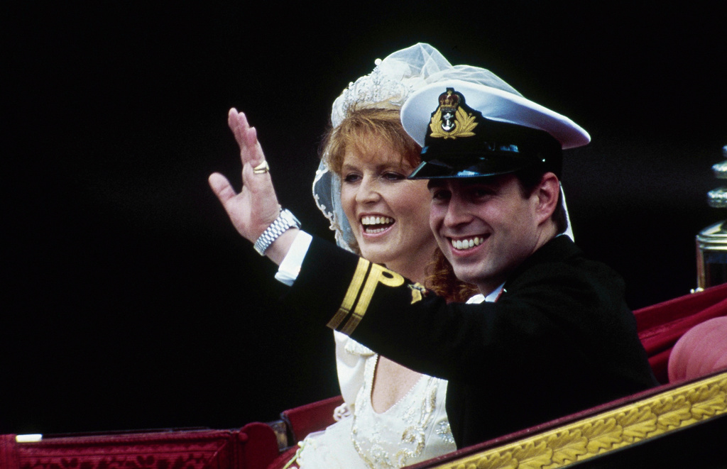 FILE - British Prince Andrew, with his bride, Sarah, waves from their horse-drawn carriage as they leave Westminster Abbey following their marriage in London, July 23, 1986. (AP Photo/Dave Caulkin, File)