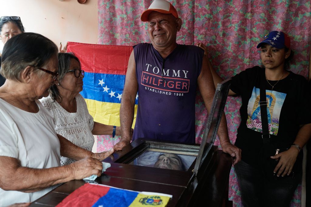 Relatives stand by the coffin of Edilson Torres, a Venezuelan police officer who died in prison a month after being arrested on accusations of treason, in Guanare, Venezuela, Tuesday, Jan. 13, 2026.. (AP Photo/Ariana Cubillos)