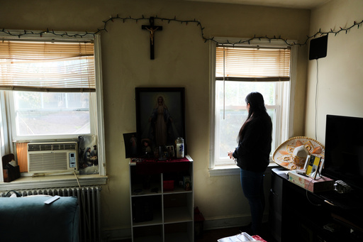 A parishioner of the Shrine of the Sacred Heart, whose husband was detained by immigration agents, looks out her home's window as she poses for a portrait in Washington, Friday, Oct. 10, 2025. (AP Photo/Luis Andres Henao) A parishioner of the Shrine of the Sacred Heart, whose husband was detained by immigration agents, looks out her home's window as she poses for a portrait in Washington, Friday, Oct. 10, 2025. (AP Photo/Luis Andres Henao)