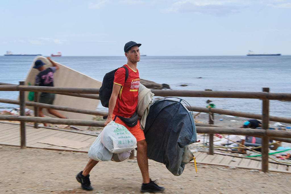 A migrant who crossed from Morocco into Spain gathers his belongings after being cleared from the beach in the Spanish exclave of Ceuta, Thursday, Aug. 20, 2026. (AP Photo/Antonio Sempere)