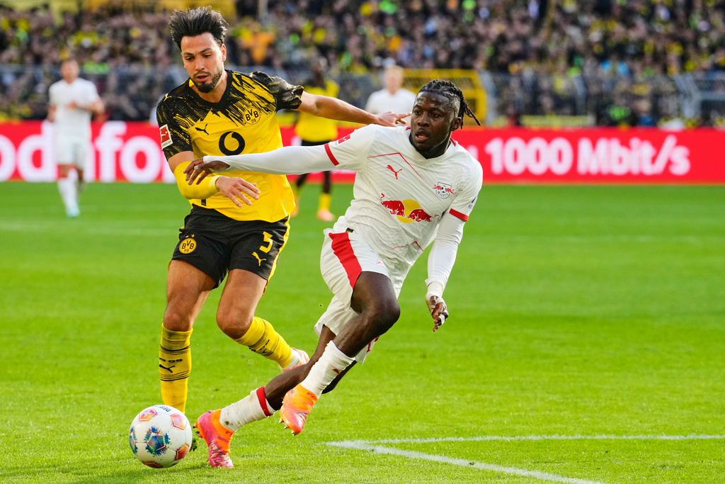 Dortmund's Ramy Bensebaini, left, and Leipzig's Johan Bakayoko challenge for the ball during the German Bundesliga soccer match between Borussia Dortmund and RB Leipzig in Dortmund, Germany, Saturday, Oct. 4, 2025. (AP Photo/Martin Meissner)