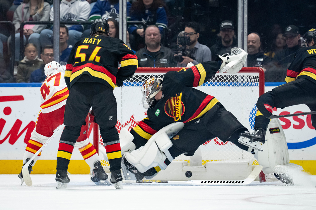 Calgary Flames' Connor Zary scores on Vancouver Canucks goaltender Kevin Lankinen as Aatu Raty (54) watches during the first period of an NHL hockey game in Vancouver, British Columbia, on Sunday, Nov. 23, 2025. (Ethan Cairns/The Canadian Press via AP)