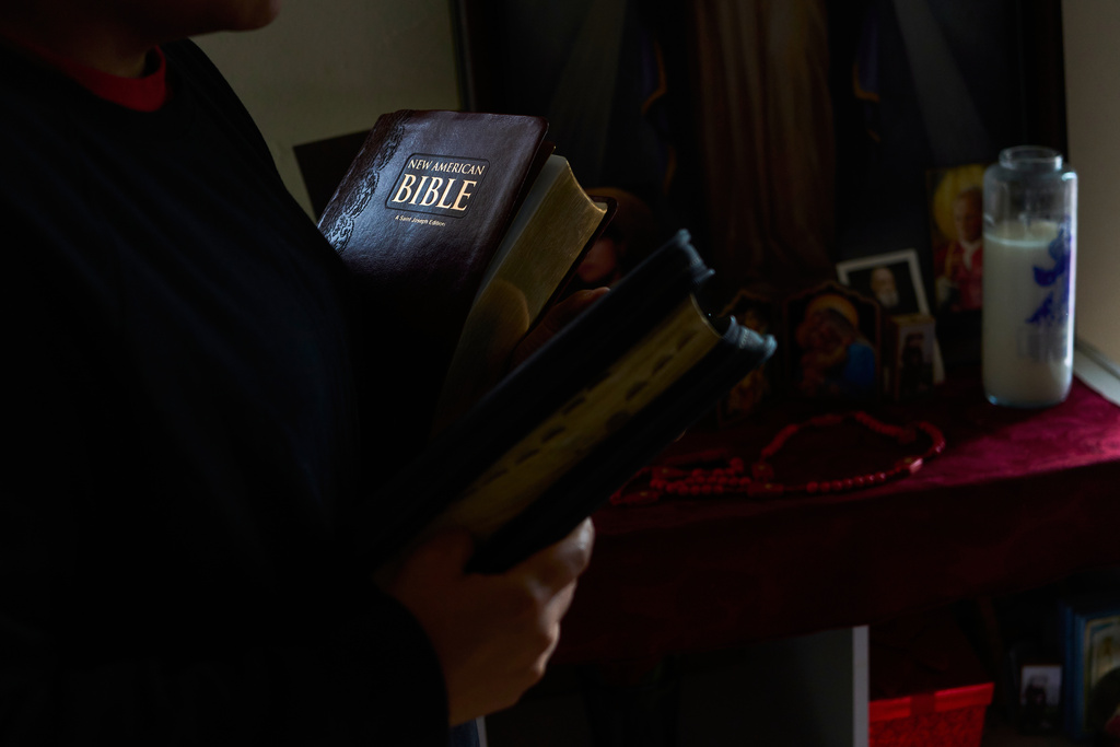 A parishioner of the Shrine of the Sacred Heart holds the Bibles of her husband who was detained by immigration agents in Washington, Friday, Oct. 10, 2025. (AP Photo/Luis Andres Henao)