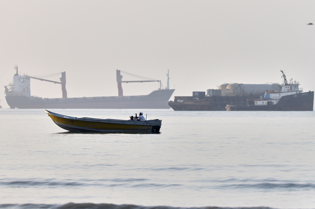 A small boat moves along the shoreline where an a cargo vessel, tugboat and industrial barge are all anchored in the Strait of Hormuz off Bandar Abbas, Iran, Monday, June 1, 2026. (Amirhosein Khorgooi/ISNA via AP)