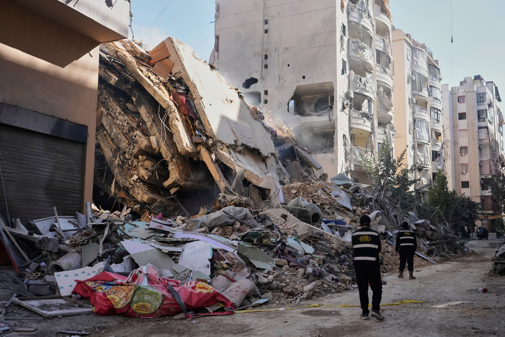 Hezbollah members walk past a building destroyed by an Israeli airstrike in Dahiyeh, Beirut's southern suburbs, Lebanon, Thursday, March 5, 2026. (AP Photo/Hassan Ammar)