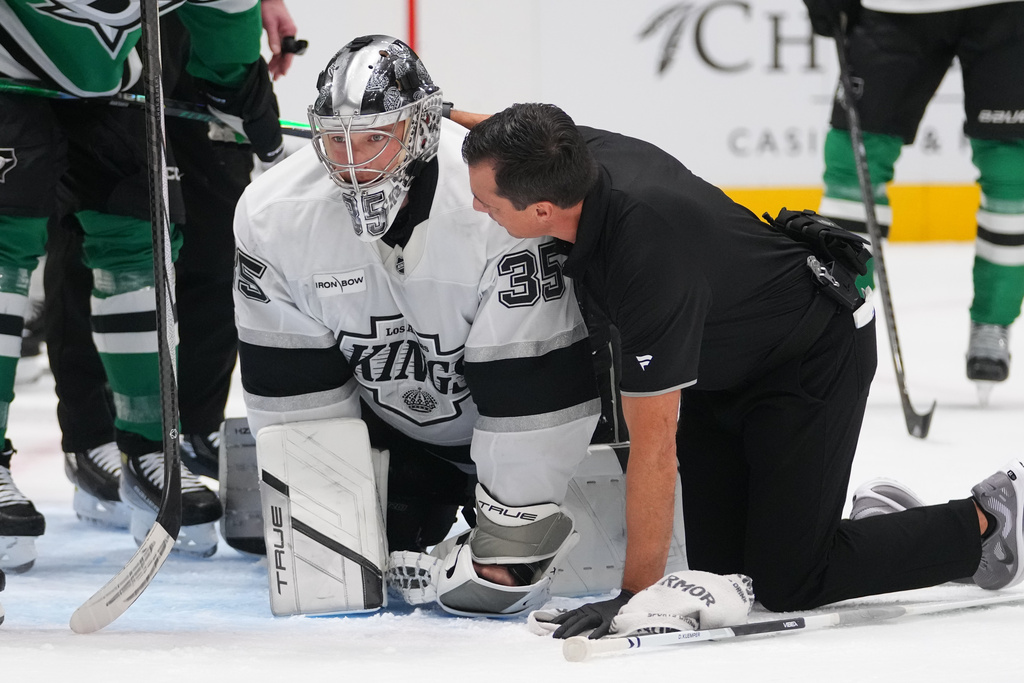 Los Angeles Kings goaltender Darcy Kuemper (35) is tended by a trainer after colliding on a play against Dallas Stars right wing Mikko Rantanen during the first period of an NHL hockey game Monday, Dec. 15, 2025, in Dallas. (AP Photo/Julio Cortez)